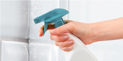 Limpieza natural para baños con Scotch-Brite, limpiando una pared con atomizador.
