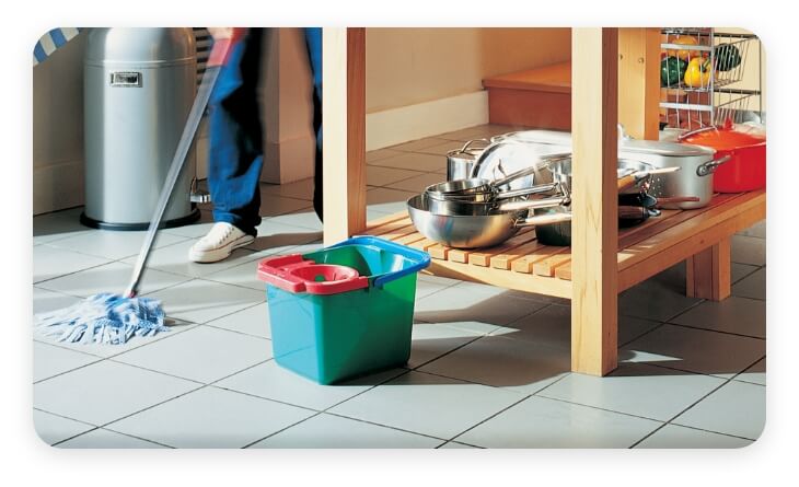 Persona trapeando el piso con una cocina de fondo