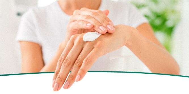 Persona untándose crema en manos para evitar resequedad después de lavar traste. 
